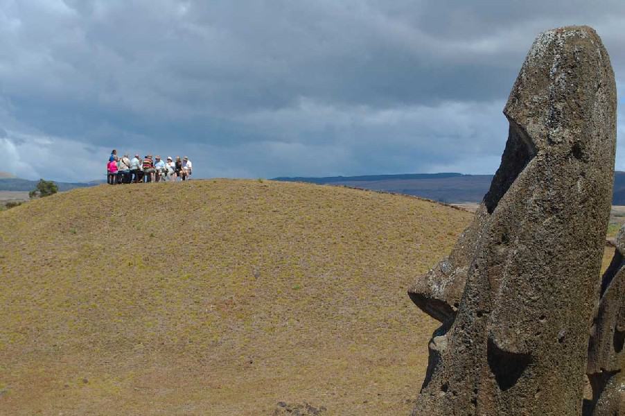 Tourist group on a hill looking at the iconic statues of Easter Island.
