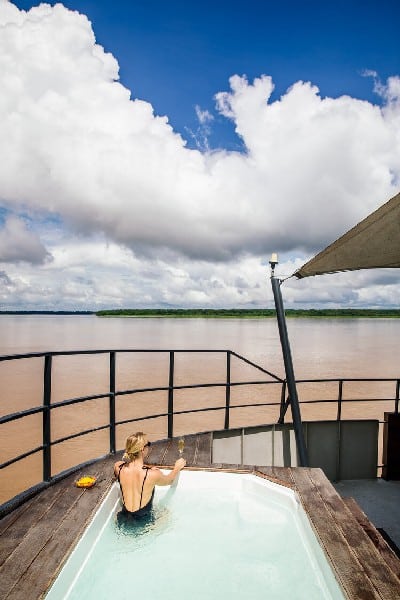 chilling in the pool on top of the Aria Amazon cruise with a view over the wide Amazon river under a beautiful sky