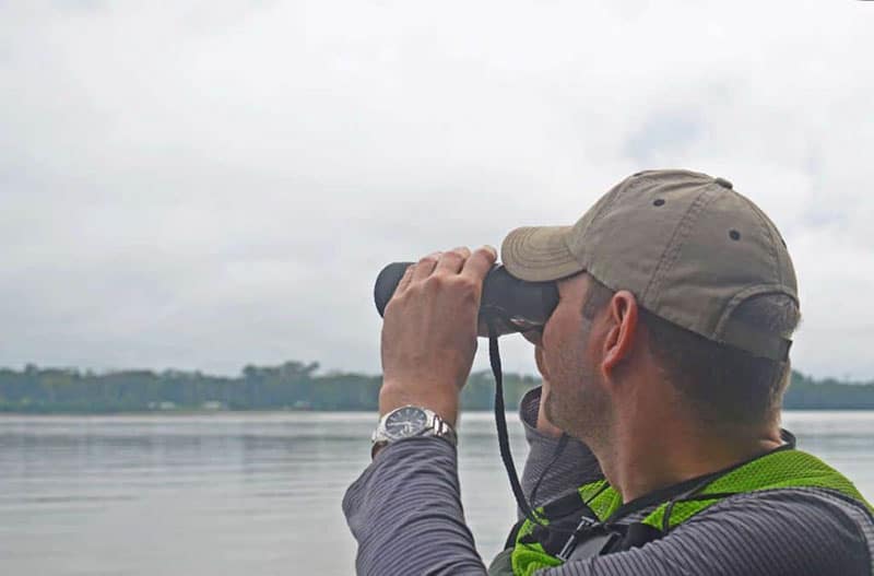 Tourist searching for birds across the Tambopata river