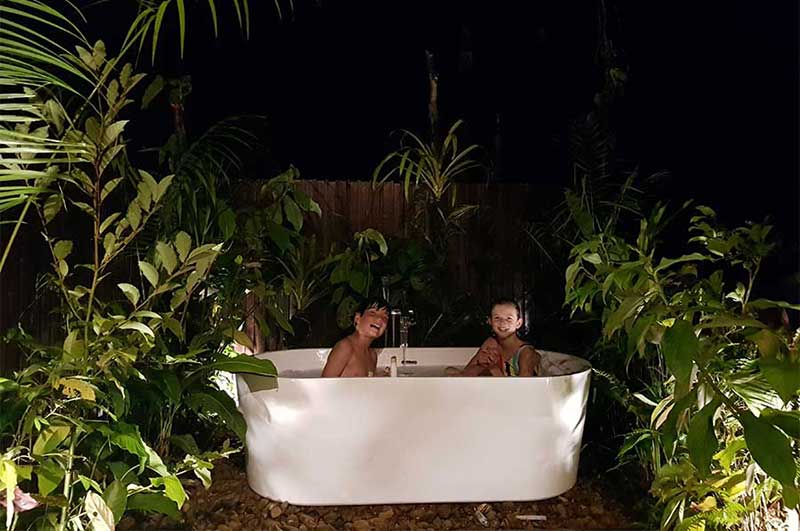 Two kids bathing in an outdoor bath in the illuminated Deluxe Suite of at TRC Tambopata Research Center (TRC)