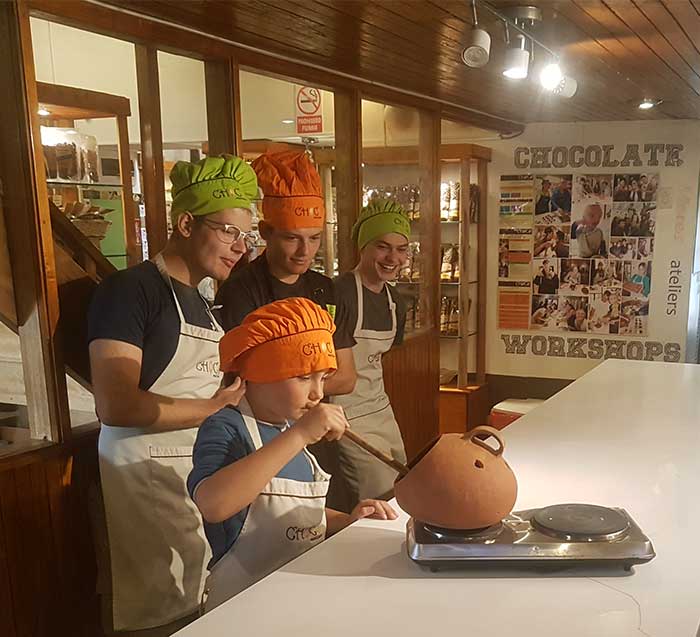 Six year old boy with 3 young men attending a workshop how to make chocolate in Cusco at the Chocomuseum