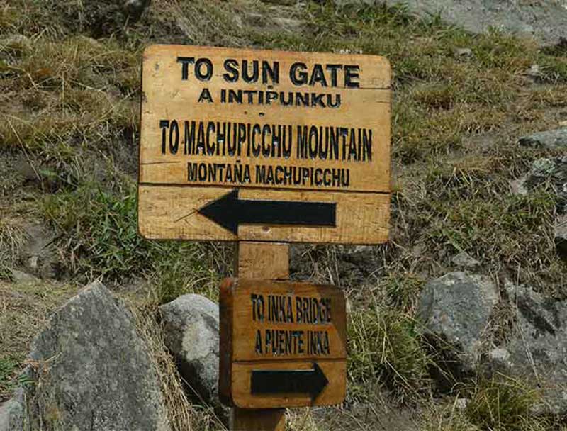 Wood board in Machu Picchu indicating the path to Machu Picchu Mountain