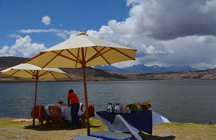 Man arranging a picnic at Huaypo Lake with views of the Andean Mountains
