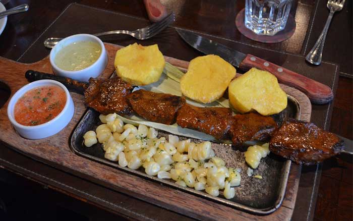 Peruvian skewer served with potatoes, corn and sauces at Panchita in Lima