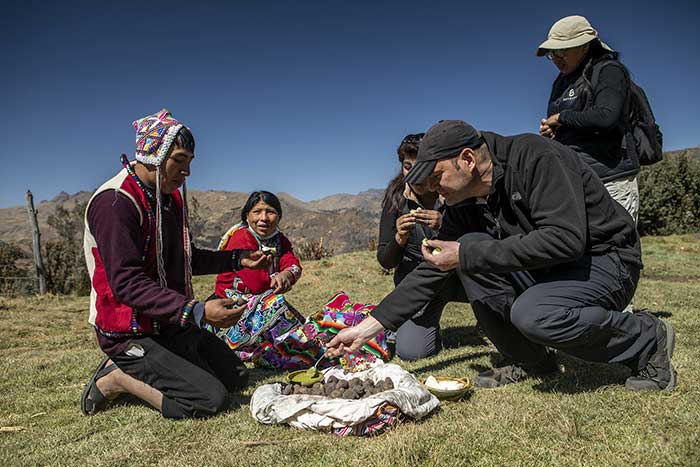 Tourist with members of the Paru Paru community tasting fresh cooked potatoes with a typical sauce in the Potato Park
