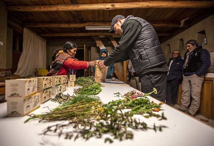 Lady giving a bag containing medicinal herbs to a tourist in the Potato Park 