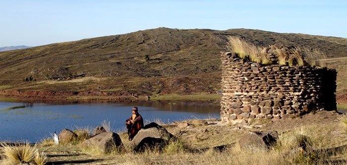 Musician in traditional attire playing local flute in Sillustani