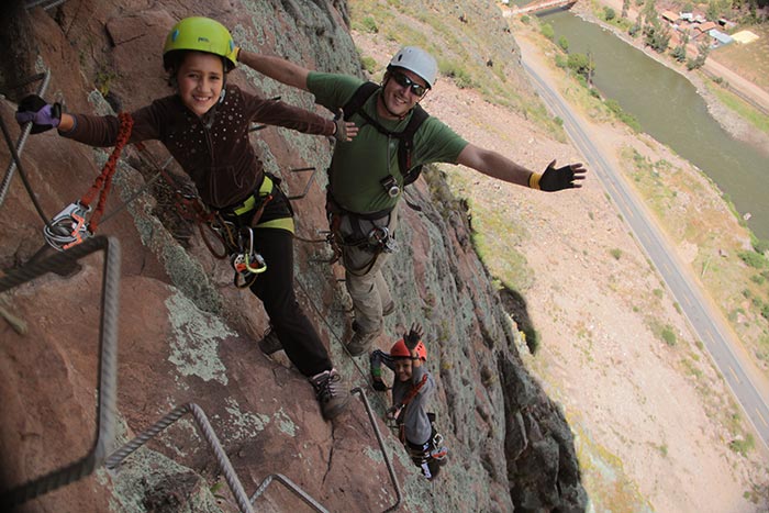 A kid & its father climbing up to the Skylodge using the via ferrata - Sacred Valley