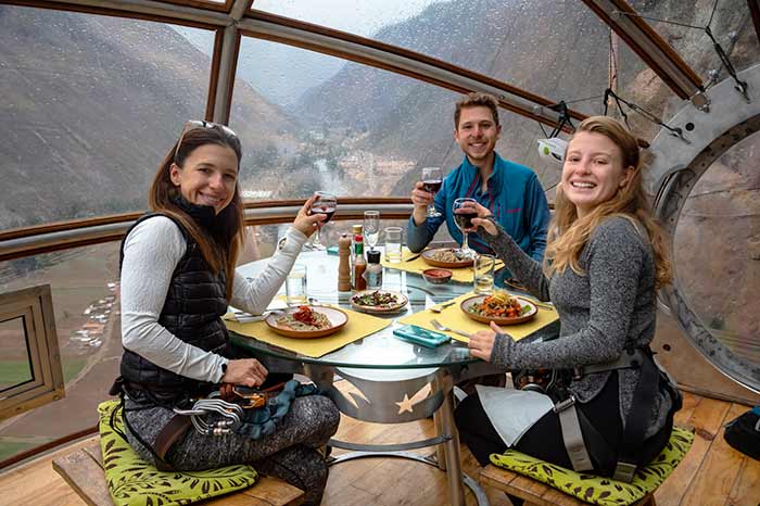 Three travelers toasting with wine at the dining pod of Skylodge Peru