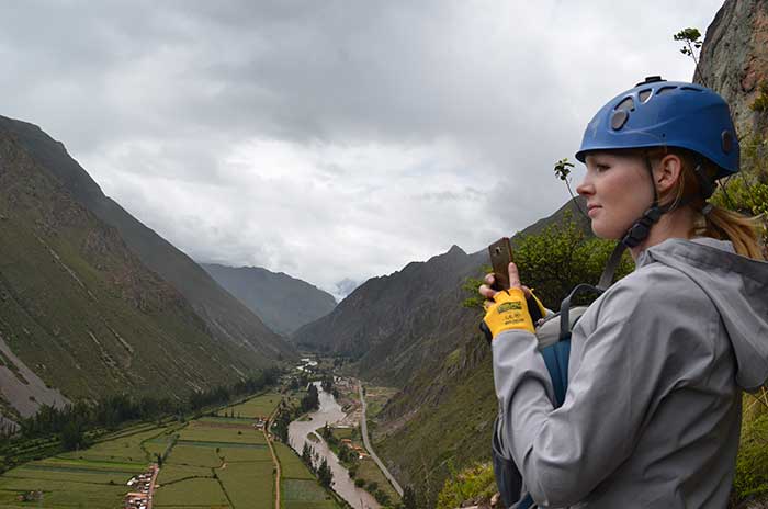 A tourist wearing climbing equipment watching over the Sacred Valley, after having reached the Skylodge