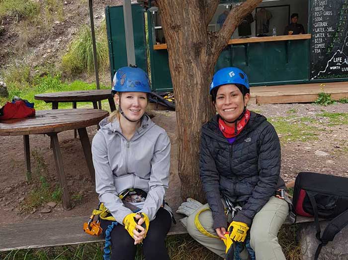 2 female guests wearing the equipment of Skylodge before climbing up to the pods, Sacred Valley, Peru