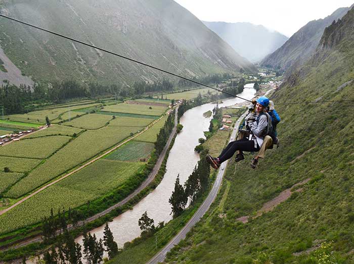 A tourist with a guide ziplining down to the Sacred Valley - Skylodge Peru