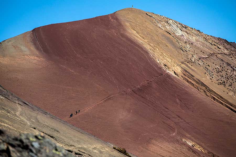 Travelers walking along the path from Rainbow Mountain to Red Valley