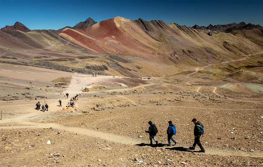 Three hikers along the path from Vinicunca Rainbow Mountain to Red Valley 