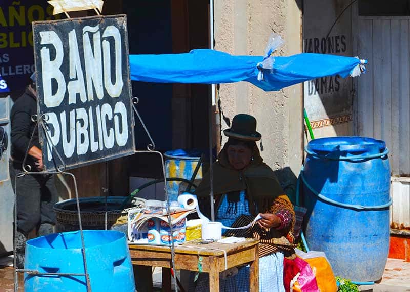 woman outside of public toilets at market in puno