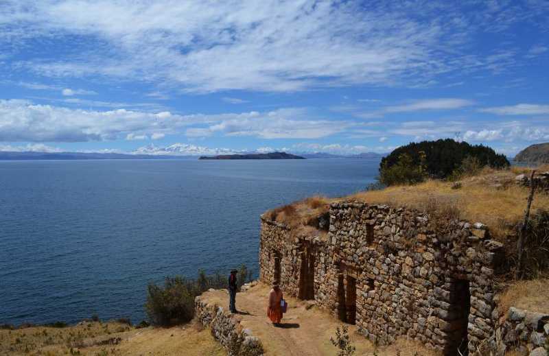 Andean in traditional attire walking on Sun Island on the Bolivian side of Titicaca Lake overlooking Moon Island