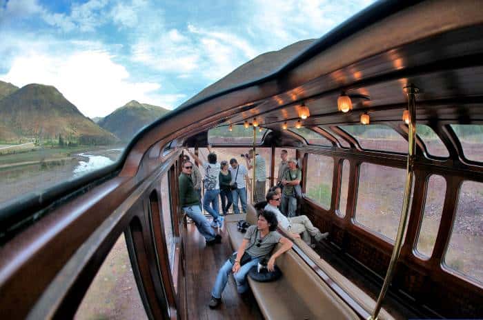 Passengers sitting and standing in the observation car of the Tititcaca Train (linking Puno with Cusco)