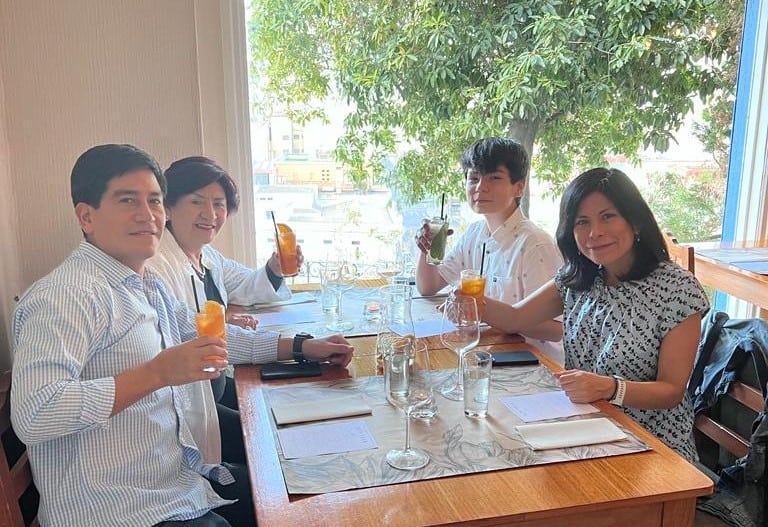 a family of 4 toasting and looking at the camera on a table with window at Caperucita y el Lobo