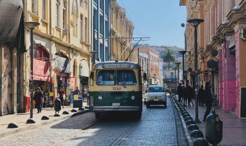 A green trolley bus crossing the cobblestone streets of the colorful harbor city of Valparaiso Chile