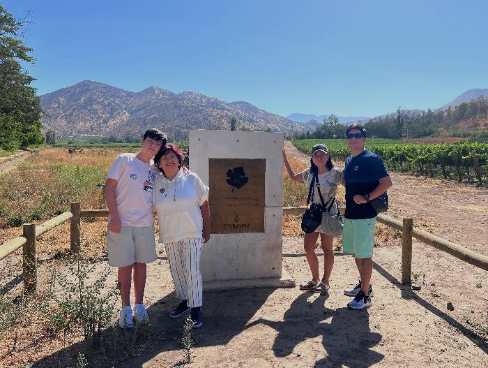 a family of four posing next to the Carmenere stone at the vineyard Santa Rita near Santiago de Chile