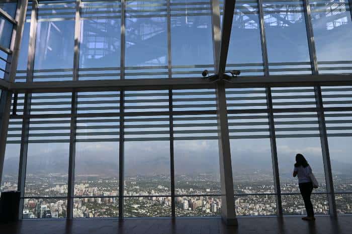 A woman across watching the Andean mountain range through a huge glass in Sky Costanera in Santiago de Chile