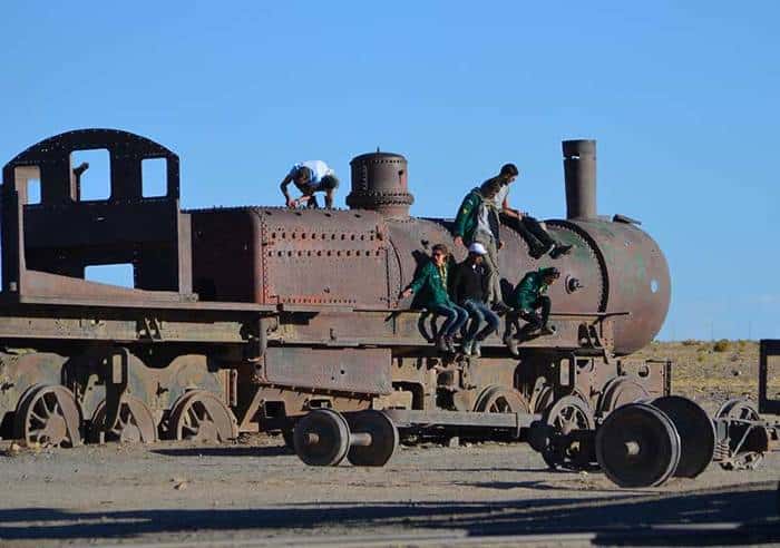 4 boys posing on a rusty train out of service in the train cemetery of Uyuni