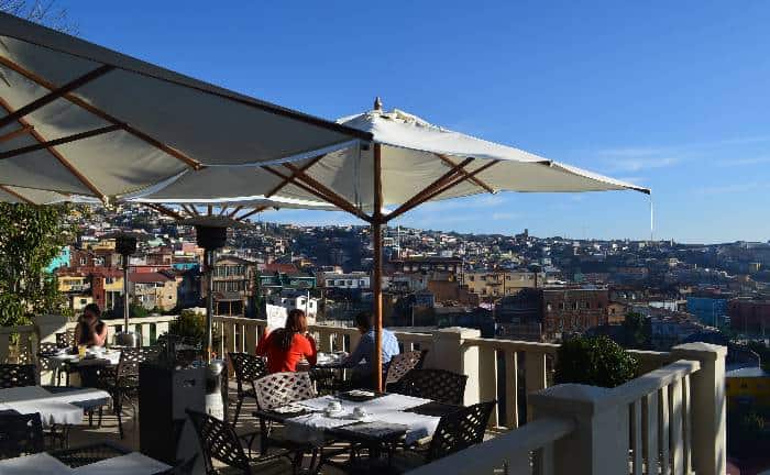 Three guests taking lunch on an outdoor terrace overlooking the colorful Valparaiso hills 