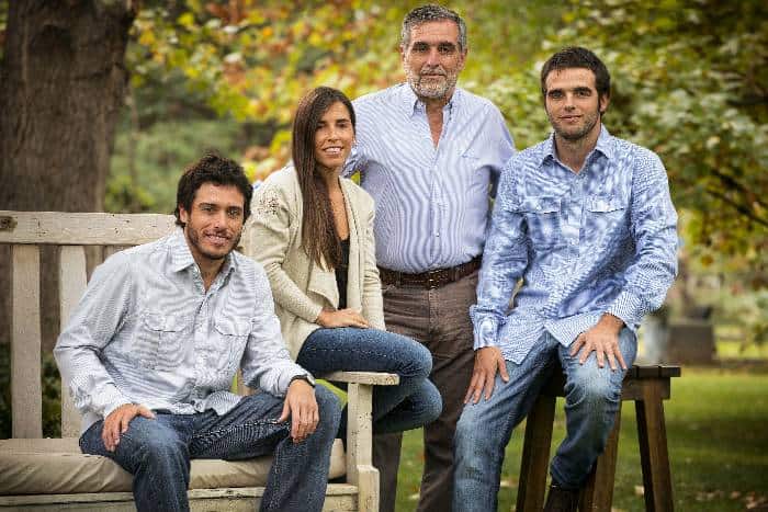 A family of four, three males and 1 females posing for the camera in dressed in casual smart style with a garden as backdrop