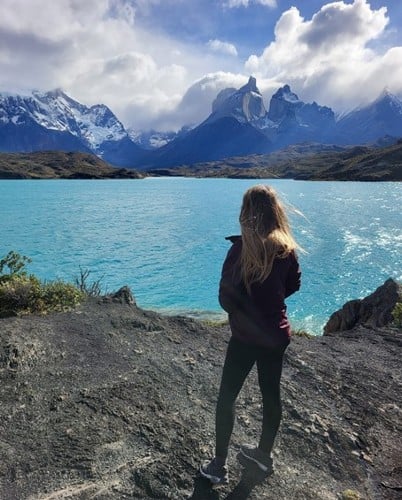 AMy standing looking across the lake over the Paine Horns in the bacground with cloud cover and blue sky