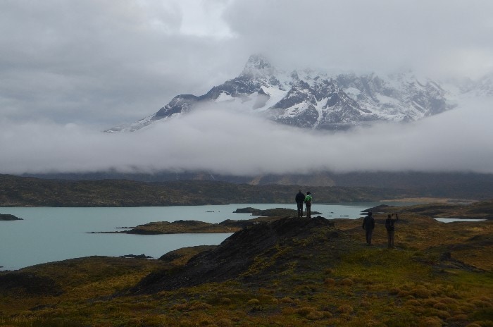 Tourists with a cloudy view over a lake overlooking the Horns of Paine in Chilean Patagonia Torres del Paine National Park