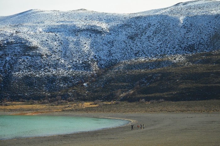 Four tourists standing on the shoreling of Laguna Amarga in Chilean Patagonia Torres del Paine National Park