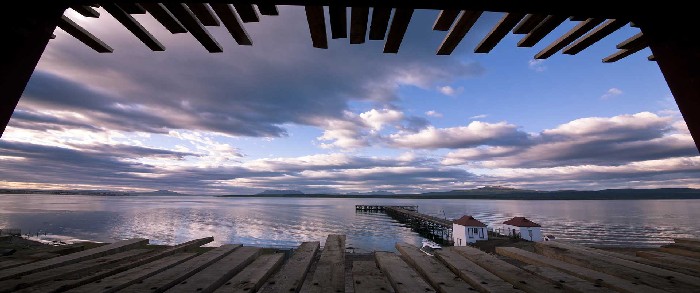 View over the lake from The Singular Patagonia at dusk with partly cloudy sky and jetty