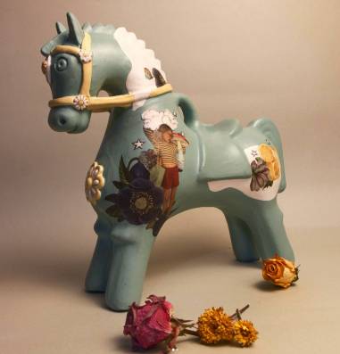 an emerald pottery horse with handmade paintings on the body and dried flowers as decoration 