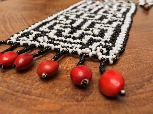 a handmade bracelet elaborated with red seeds and black and white beads 