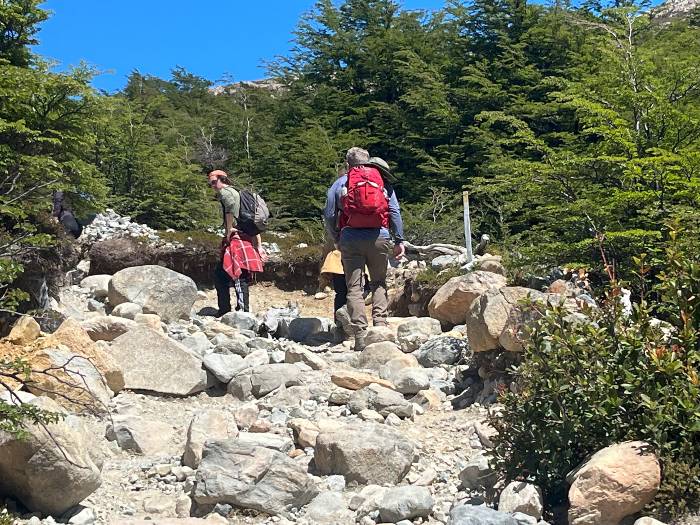 Two hikers on an even terrain with rocks of different sizes in Argentine Patagonia. Both on their way to Laguna de los Tres